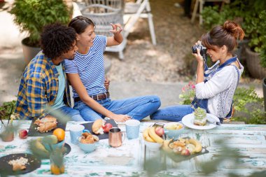 Dışarıda genç bir çiftin fotoğrafını çeken bir kadın.