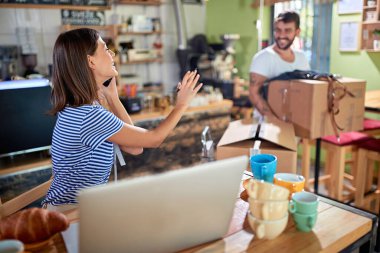 Kadın cep telefonuyla konuşuyor, ortağına taşıdığı kutuları taşımayı bırakmasını söylüyor. Kendi kafeyi açmak için son hazırlıklar yapılıyor.