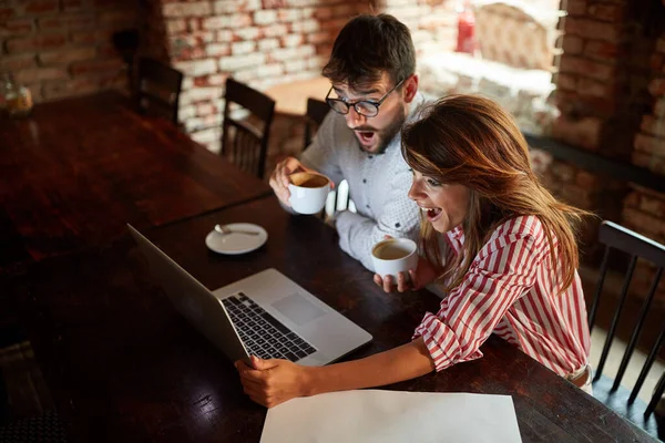 カフェに座って一緒に笑ってコーヒーを楽しむ若者たち — ストック写真