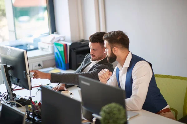 one colleagues showing to another content on computer monitor in the office at work. conversation, boss, employee, casual business concept