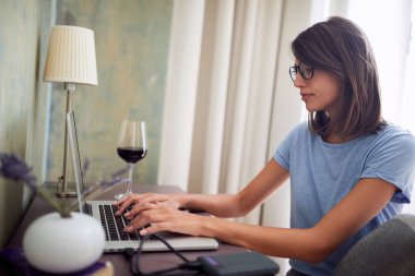 Dizüstü bilgisayar kullanan bir kadın. Evden uzak bir iş. Evde internet işi. Dizüstü bilgisayarda çalışan serbest çalışan kız..
