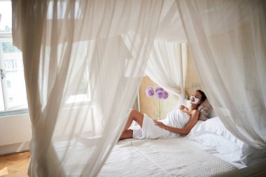 Evde yatağında kilden maskeli genç bir kadın yatıyor..