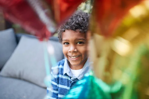 Kıvırcık Saçlı Genç Afrikalı Çocuk Renkli Balonlar Arasında Kameraya Bakıyor — Stok fotoğraf