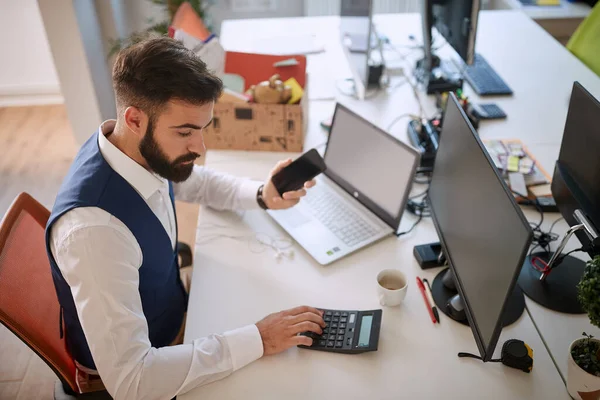 Egy Fiatal Üzletember Számológépet Használ Irodában Adatokat Dolgoz Fel Mobiltelefont — Stock Fotó