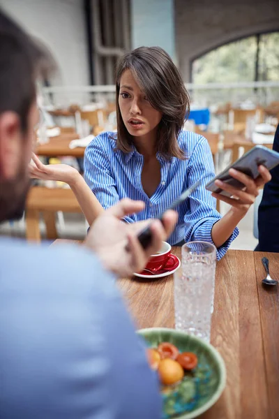 テーブルの上で働いてカフェで議論する若いビジネス女性 — ストック写真