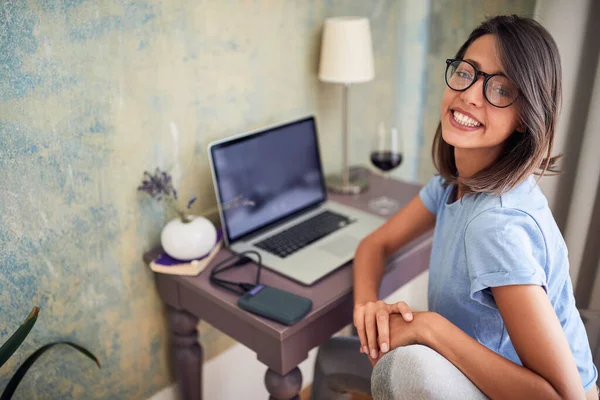 漂亮的成年女性高加索人看着相机 面带微笑 坐在笔记本电脑前的办公桌前 从家里工作 Home Office Leisure Chat Online Technology — 图库照片