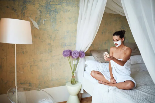아름다운 다리를 수건으로 침대에 거울에 얼굴을 마스크를 있습니다 — 스톡 사진