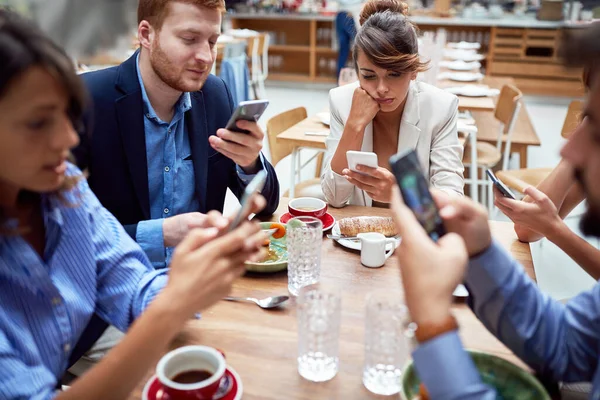 若い白人のグループは レストランでは 携帯電話を使用して非社交的なランチをしており お互いに話をしていません 現代の技術社会問題 — ストック写真