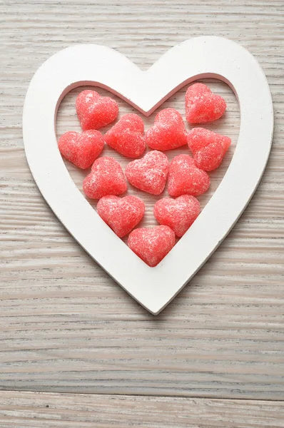 Valentine's Day. Wooden heart filled with heart shape candy — Stock Photo, Image