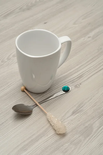 A white mug with a sugar stick and a teaspoon isolated — Stock Photo, Image