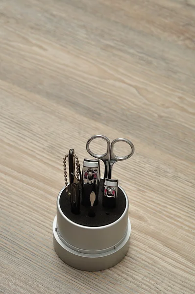 Un juego de manicura o herramientas en un recipiente sobre un fondo de madera — Foto de Stock