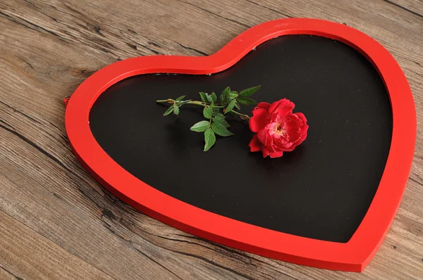 Día de San Valentín. Una pizarra en forma de corazón con una rosa roja — Foto de Stock