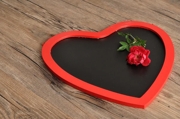 Día de San Valentín. Una pizarra en forma de corazón con una rosa roja — Foto de Stock