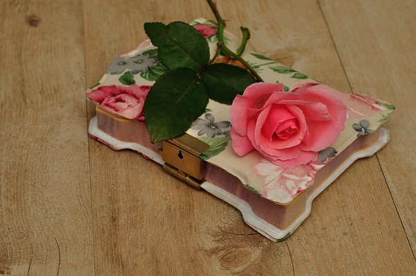 Um caderno fechado com uma flor rosa — Fotografia de Stock