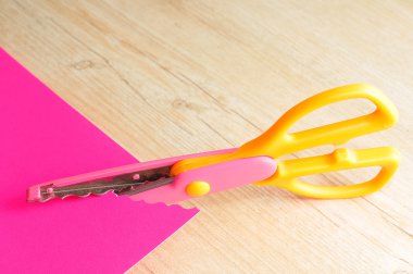 Kesme pembe bir kağıt bir zikzak desen renkli bir makas 