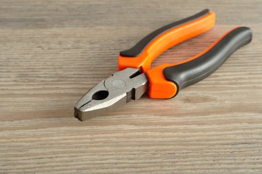 Ahşap arka plan üzerinde izole bir turuncu ve siyah pense