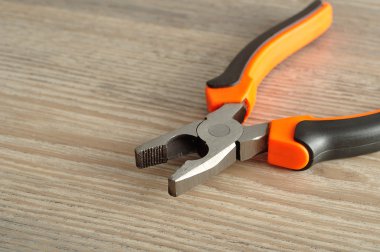 Ahşap arka plan üzerinde izole bir turuncu ve siyah pense