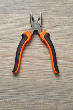 Ahşap arka plan üzerinde izole bir turuncu ve siyah pense