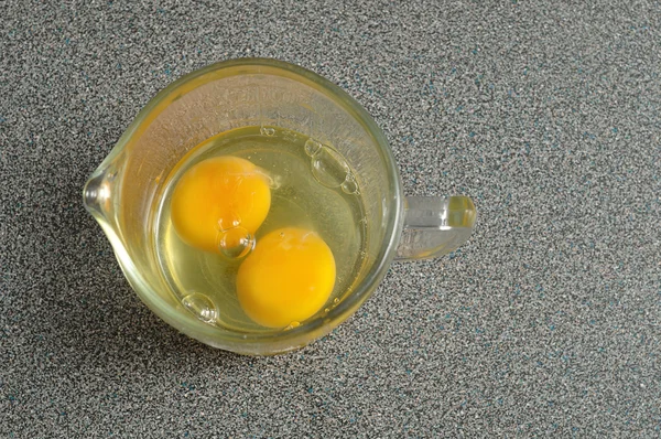 Dwa surowe jaja w miarce na szary Blat — Zdjęcie stockowe