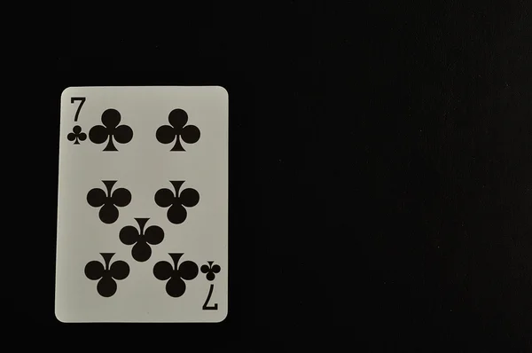 Jugando a cartas. Siete de tréboles aislados sobre un fondo negro —  Fotos de Stock