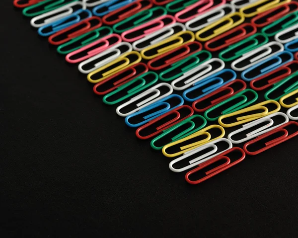 Linhas de clipes de papel coloridos em um fundo preto — Fotografia de Stock