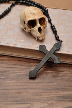 Vervet monkey skull with rosary beads on top of an old book clipart