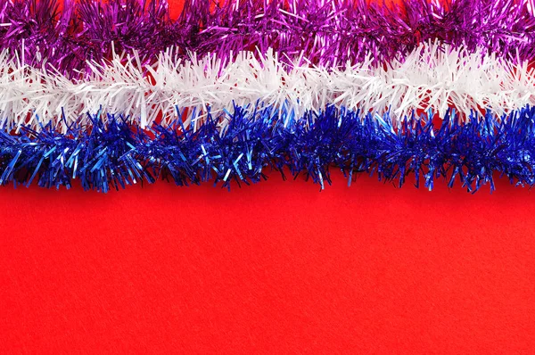 Filas de oropel colorido aisladas sobre un fondo rojo — Foto de Stock