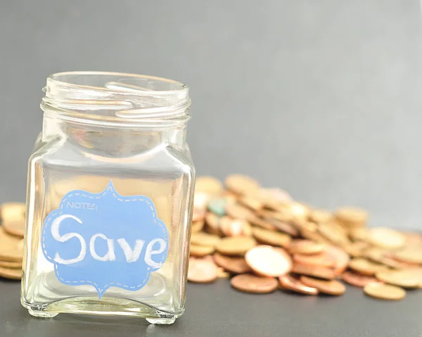 An empty jar with the word save on it and coins