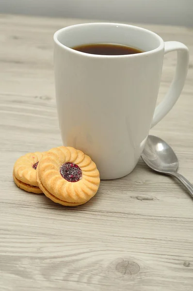 A white mug with coffee and round jam filled biscuits — Stock Photo, Image