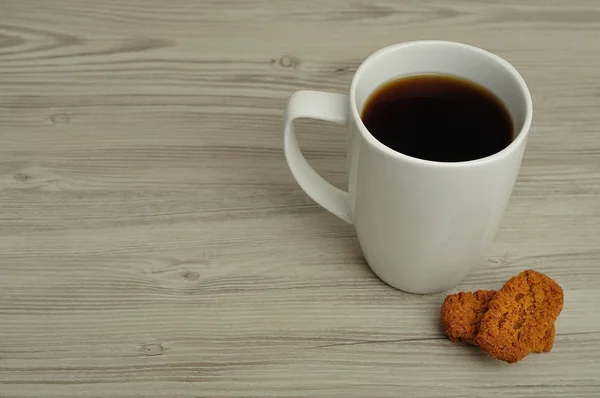 A white mug with coffee and golden square biscuits — Stock Photo, Image