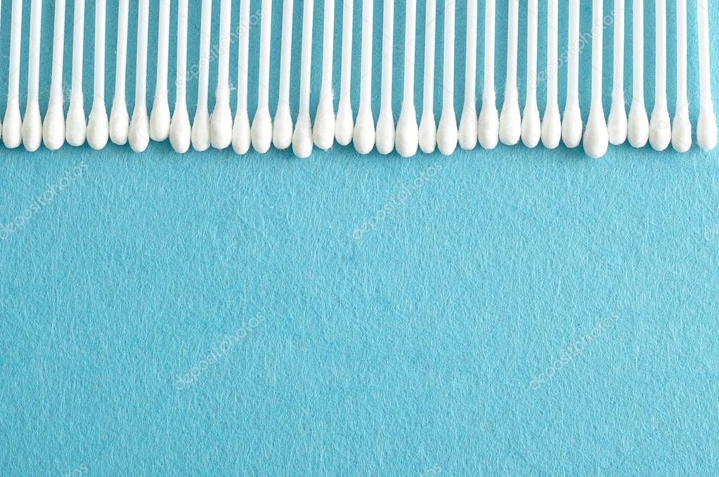 A row of cotton swabs isolated on a light blue background