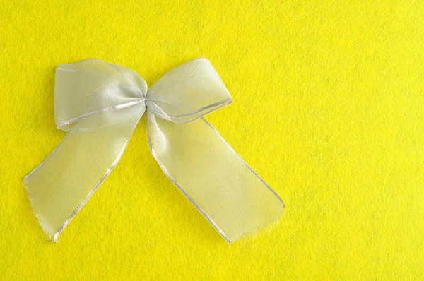 A silver bow isolated against a yellow background — Stock Photo, Image