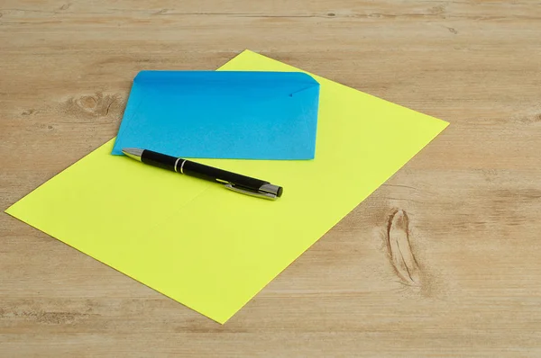 A yellow paper and a blue envelope with a black pen — Stock Photo, Image