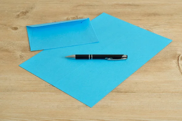 Un papier bleu et une enveloppe avec un stylo noir — Photo