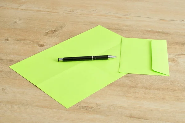 A green paper and envelope with a  pen — Stock Photo, Image