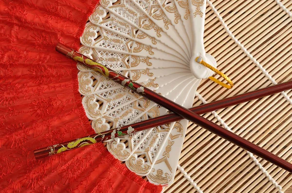 Un ventilateur à main rouge avec un ensemble de baguettes rouges — Photo