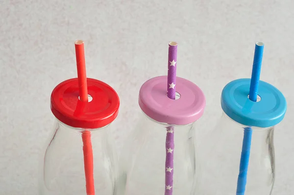 Three glass bottles with straws in the lids — Stock Photo, Image