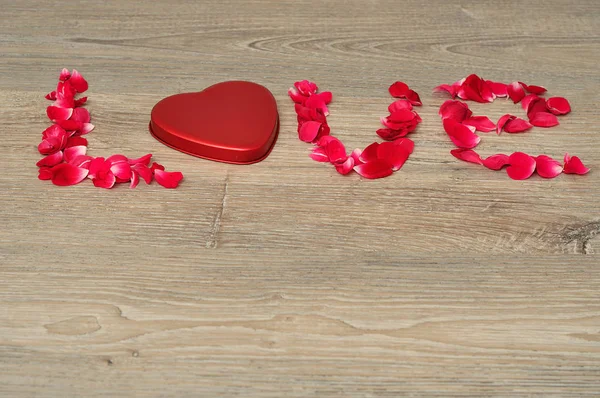 Amor soletrado com pétalas de rosa vermelha e uma forma de coração lata Imagem De Stock