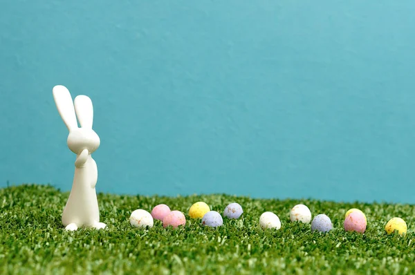 Biały królik plastikowe figurki i nakrapiane jaja wielkanocne — Zdjęcie stockowe