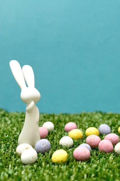 A white plastic bunny figurine and speckled easter eggs — Stock Photo, Image