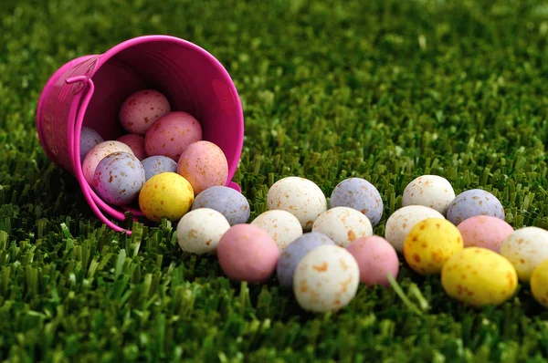 Small speckled easter eggs spilling out of a pink bucket — Stock Photo, Image