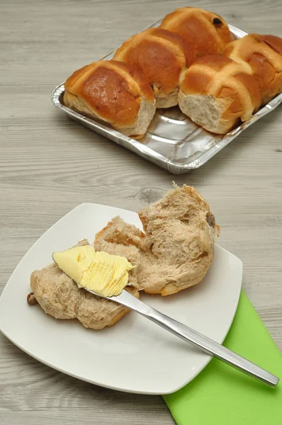 Hot salib roti, mentega, pisau dan serbet hijau di atas meja — Stok Foto