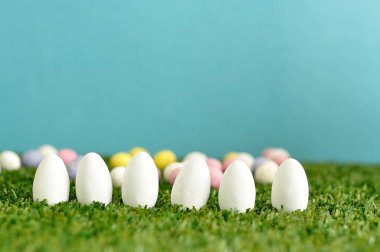Satır yapay çim üzerinde görüntülenen beyaz Paskalya yortusu yumurta