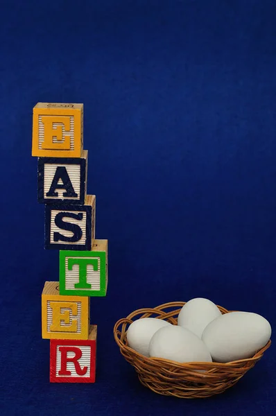 Πάσχα γράφεται με μπλοκ αλφάβητο και ένα καλάθι με αυγά — Φωτογραφία Αρχείου