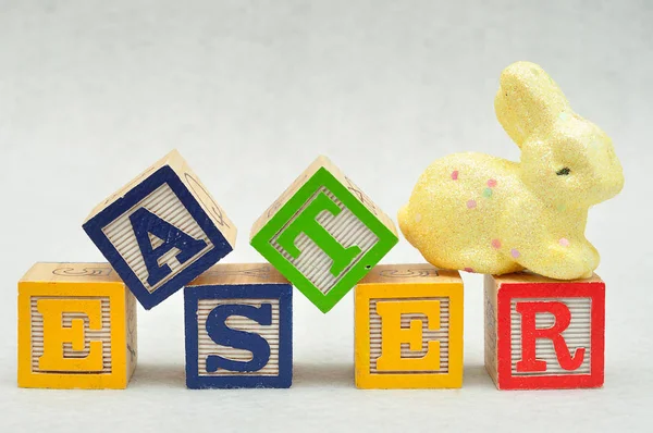 Ostern buchstabiert mit Buchstabenblöcken und einem gelben Hasen — Stockfoto