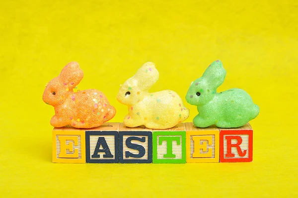 Páscoa soletrada com blocos de alfabeto e coelhos coloridos — Fotografia de Stock