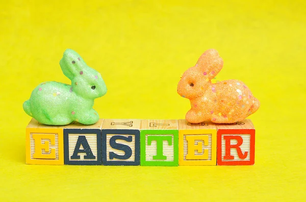 Páscoa soletrada com blocos de alfabeto e coelhos coloridos — Fotografia de Stock