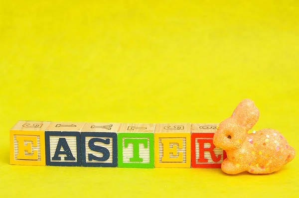 Ostern buchstabiert mit Buchstabenblöcken und einem orangefarbenen Hasen — Stockfoto