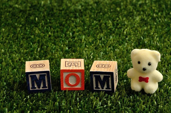 Maman orthographiée avec des blocs d'alphabet colorés et un ours en peluche blanc — Photo