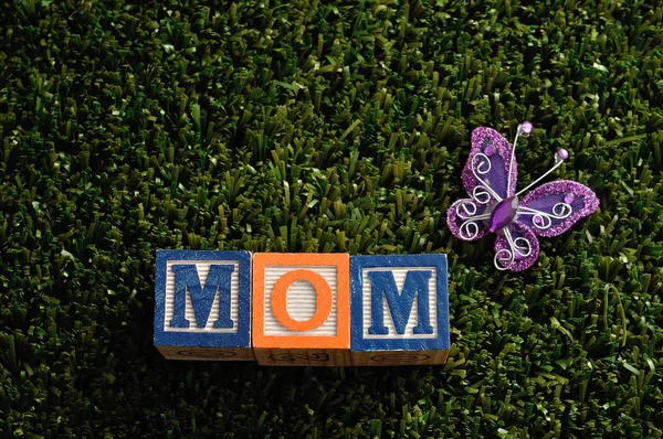 Maman épelée avec des blocs d'alphabet colorés et un papillon en soie — Photo